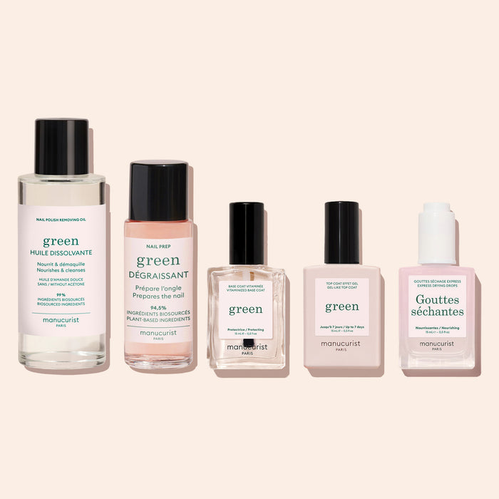 Five bottles of Manucurist nail products are arranged side by side on a light beige background, each featuring a different label and shade of liquid. The selection includes the plant-based Nail Polish Removing Oil, as well as polish removers, nail prep solutions, acetone-free top coats, and nourishing treatments.
