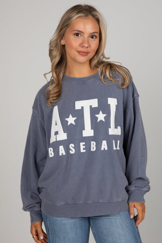 Woman wearing a blue sweatshirt with 'ATL Baseball' text on a gray background