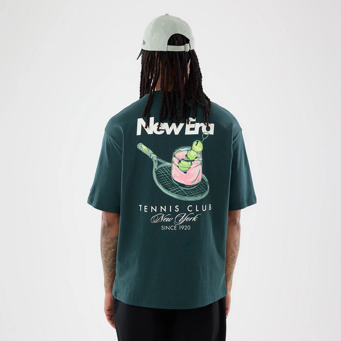 The model is wearing this New Era Tennis Graphic Oversized T-Shirt in dark green. 2