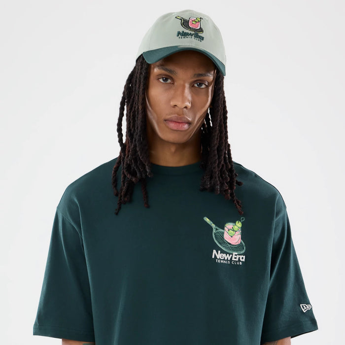 The model is wearing this New Era Tennis Graphic Oversized T-Shirt in dark green. 3