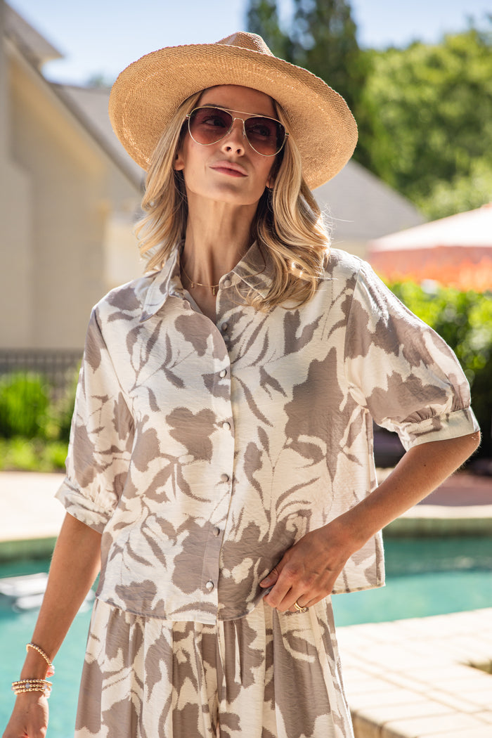 Woman wearing a floral top and sun hat by a poolside