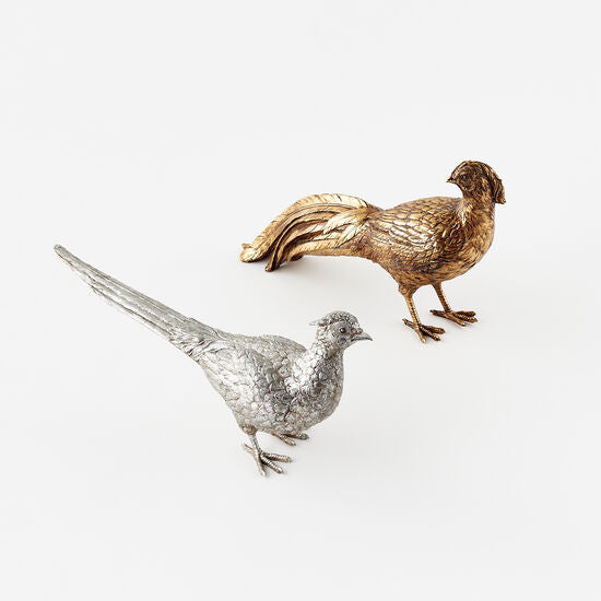 Decorative bird figurines, one silver and one gold, on a white background