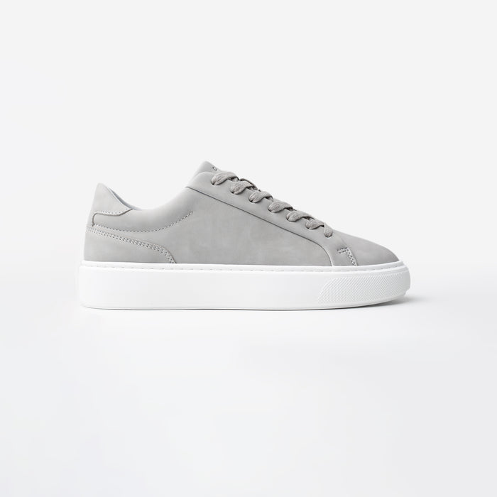 Side view of the Premium Classic Trainer in Grey, featuring a clean white PU upper, grey faux suede heel, white lace-up fastening and cushioned cup sole.