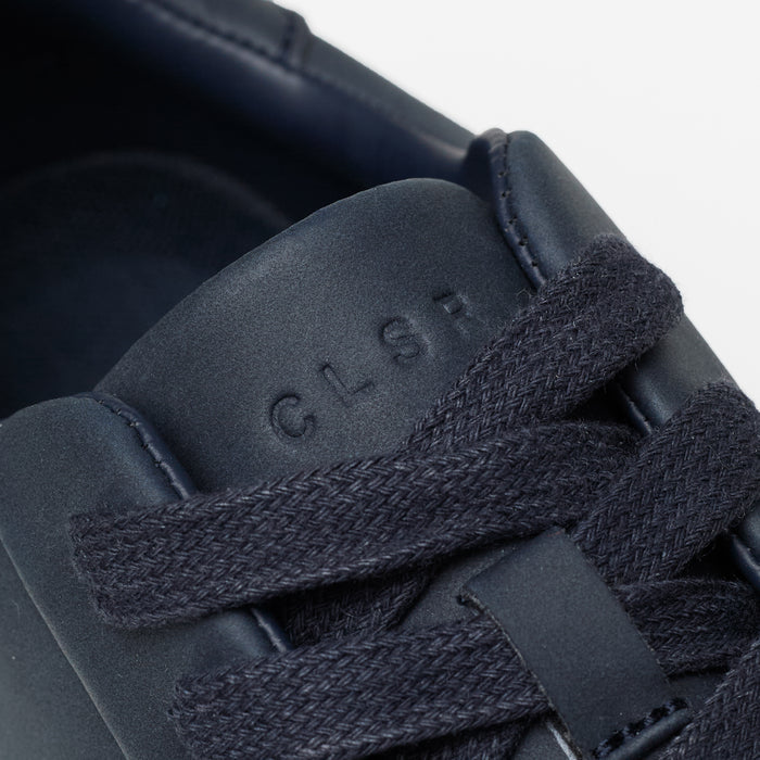 Close-up of the Premium Classic Trainer in navy, highlighting the navy textured laces, smooth PU upper and debossed CLSR tongue branding.