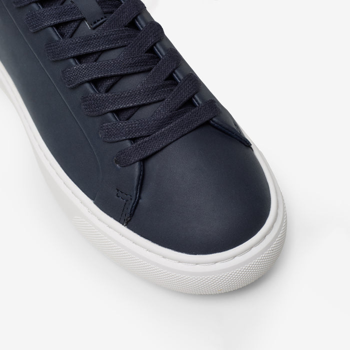 Close-up of the Premium Classic Trainer in navy, highlighting the smooth navy PU toe box, tonal lace-up fastening, stitching and textured cup sole.