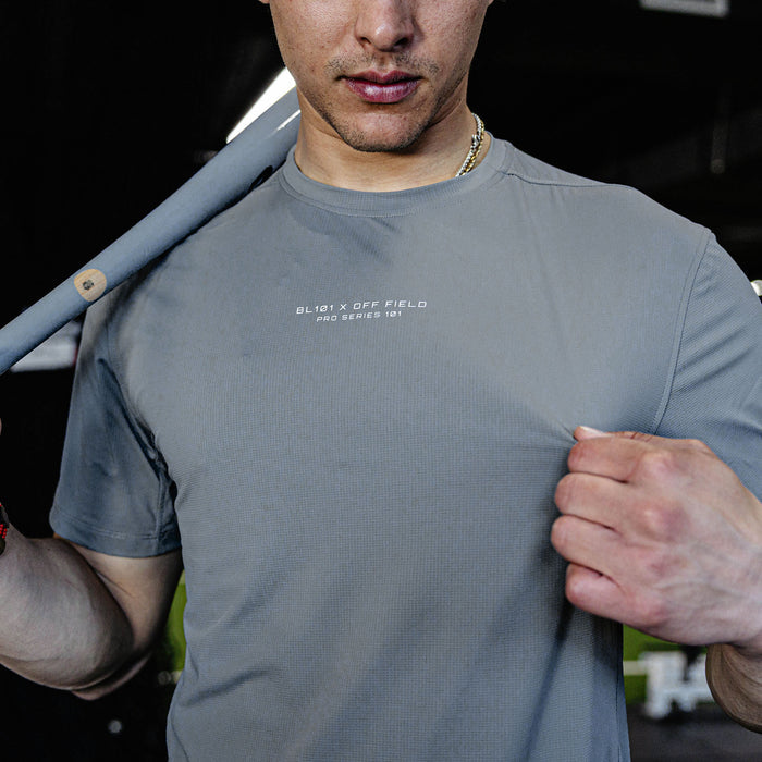 Man wearing a gray t-shirt with text, standing next to a car.