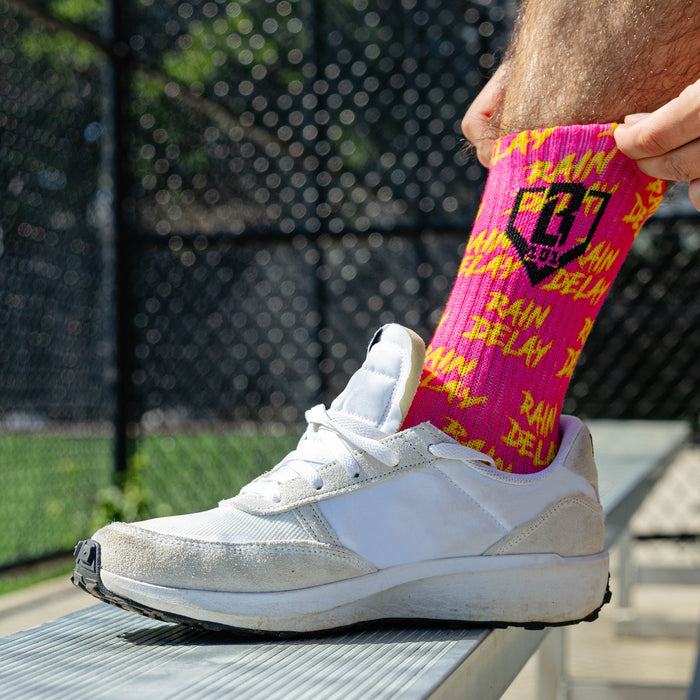 Adult model wearing multi-color socks with "Rain Delay Performance  3-Pack" design
