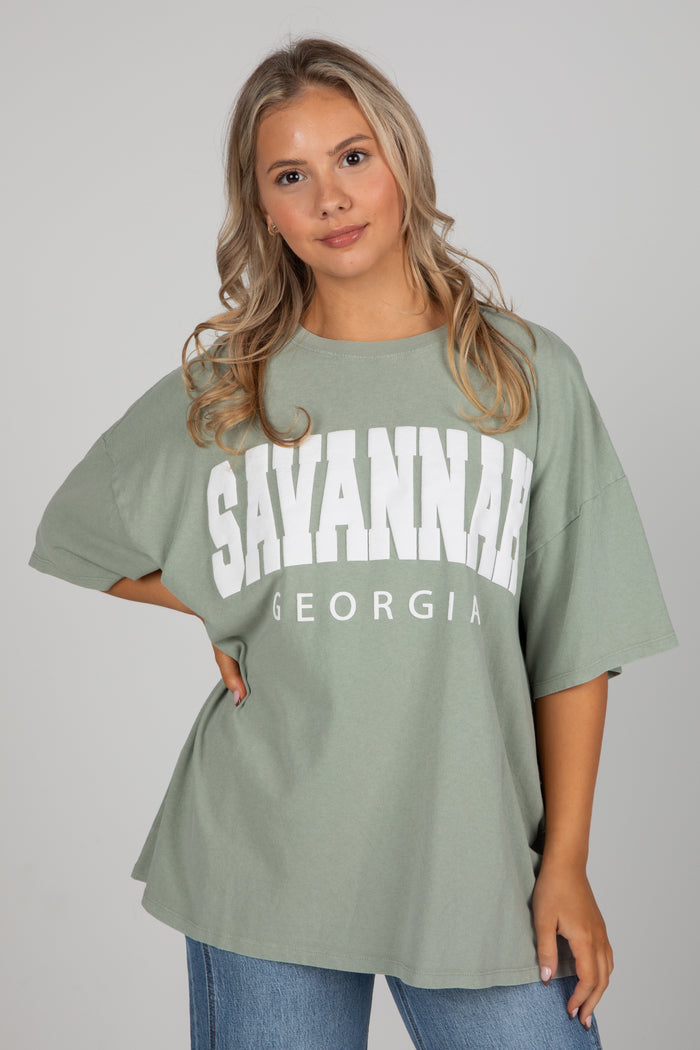 Woman wearing a green t-shirt with 'Savannah, Georgia' text on a plain background