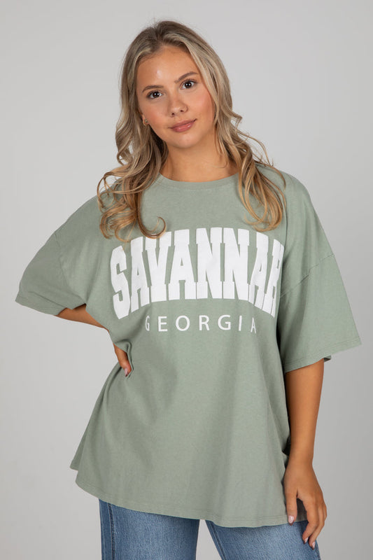 Woman wearing a green t-shirt with 'Savannah, Georgia' text on a plain background