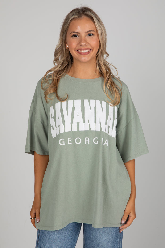 Woman wearing a green t-shirt with 'Savannah, Georgia' text on a plain background