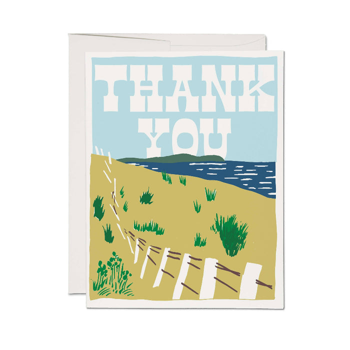 A folded thank you card with an illustration of a seaside scene, including a pathway, grass, and ocean in the background, with the words 'THANK YOU' prominently displayed.