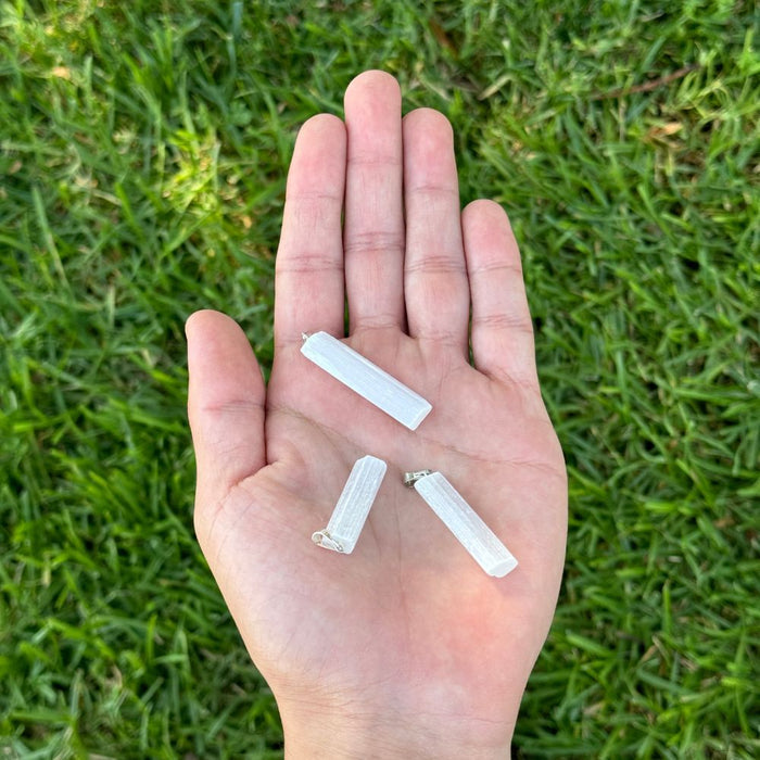 Hand holding threePoint Pendant - Selenite against a grass background