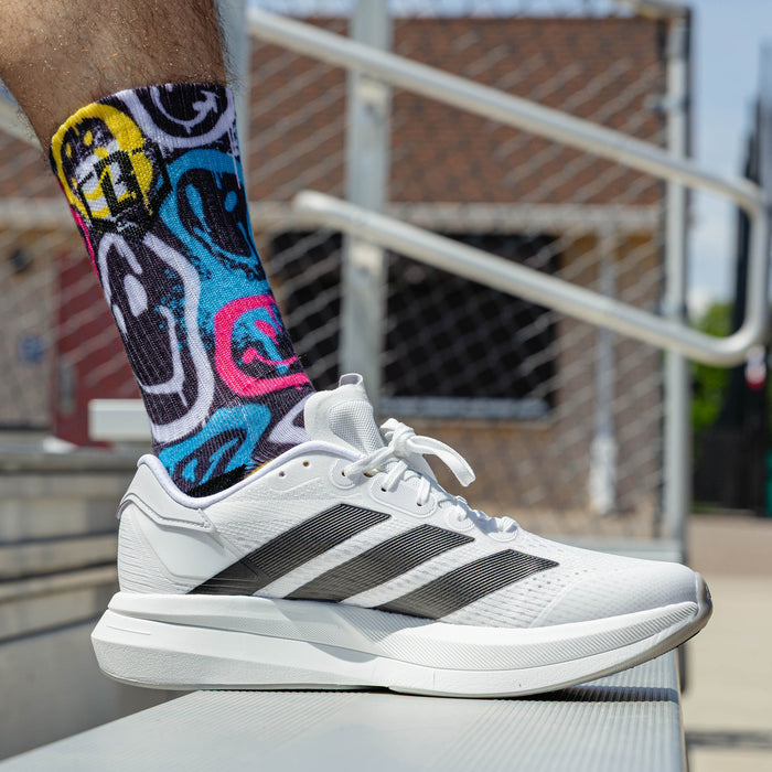 Adult model wearing multi-color socks with "Smiley Slugger Performance  3-Pack" design