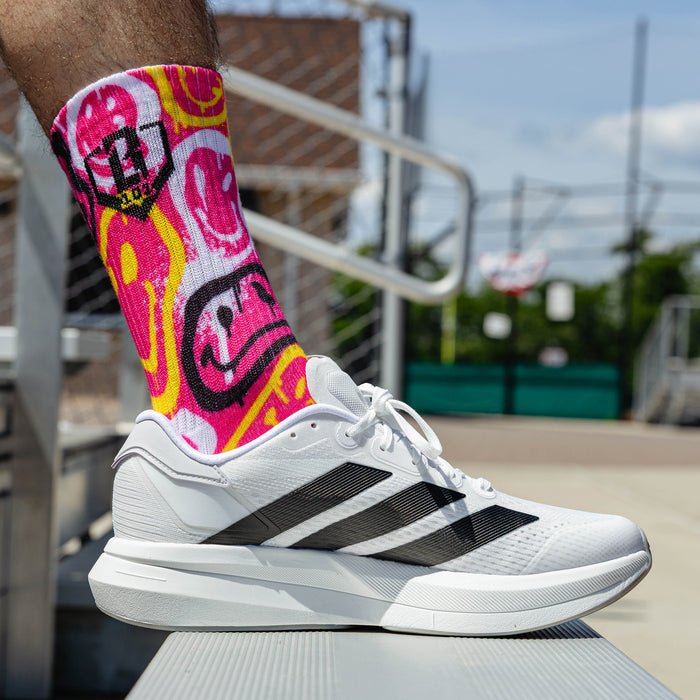 Adult model wearing multi-color socks with "Smiley Slugger Performance  3-Pack" design