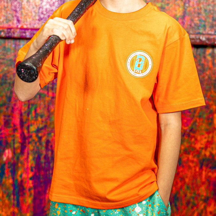Person wearing an orange t-shirt with a BL101 logo, holding a bat against a colorful background
