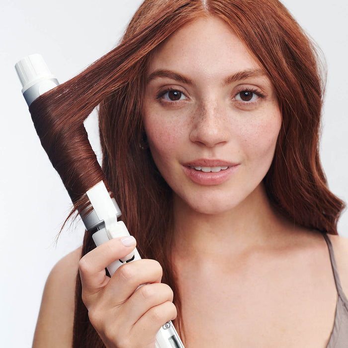 Woman with long red hair using Stylewinder to curl hair
