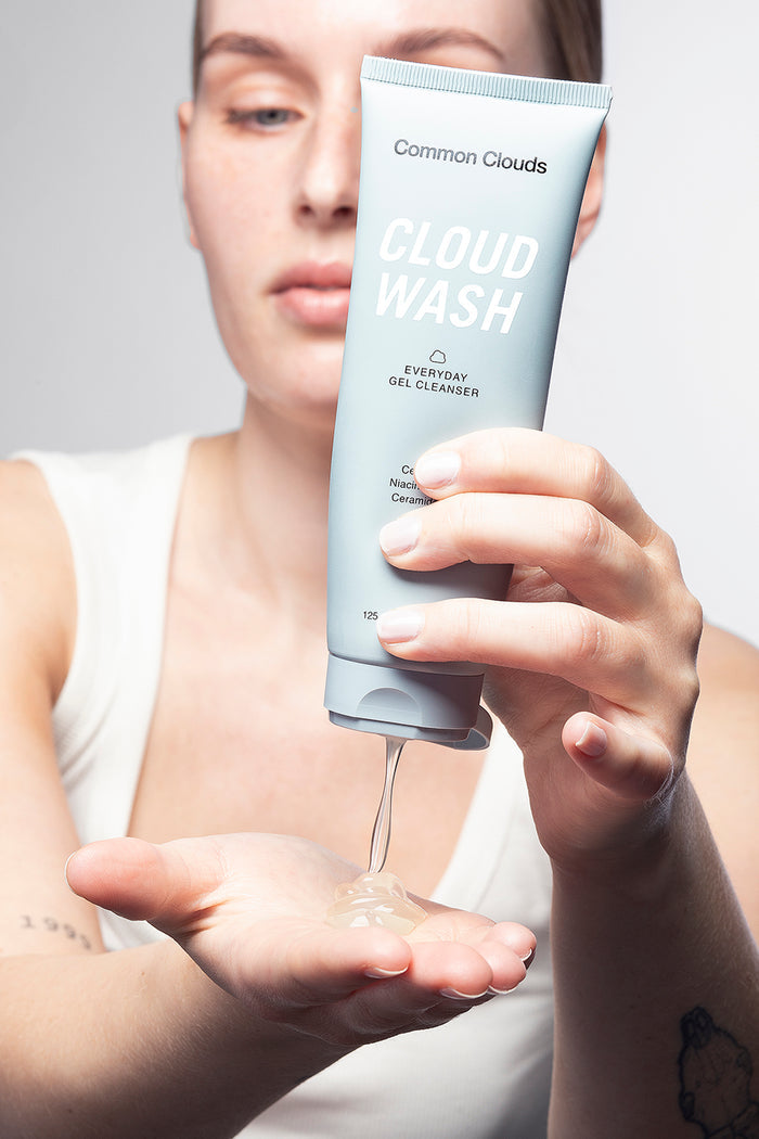 Person holding a tube of 'Cloud Wash' cleanser with visible Common Clouds  brand name.